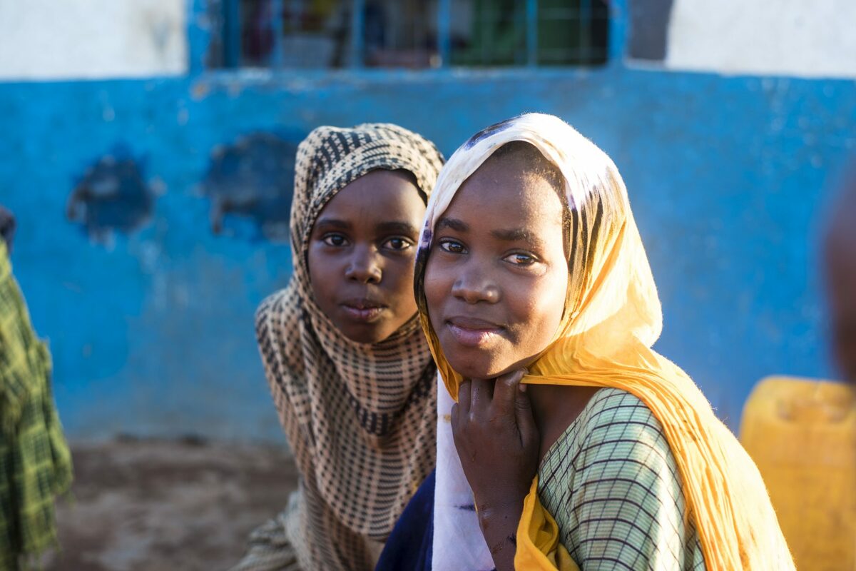 zwei junge somalische Mädchen mit bunten Kopftüchern lächeln in die Kamera