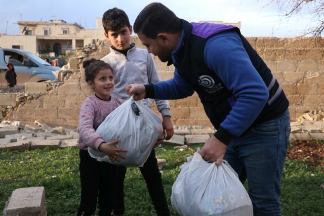 ein Mitarbeiter der arche noVa Partnerorganisation Bonyan verteilt Hilfgüter an Kinder in Afrin