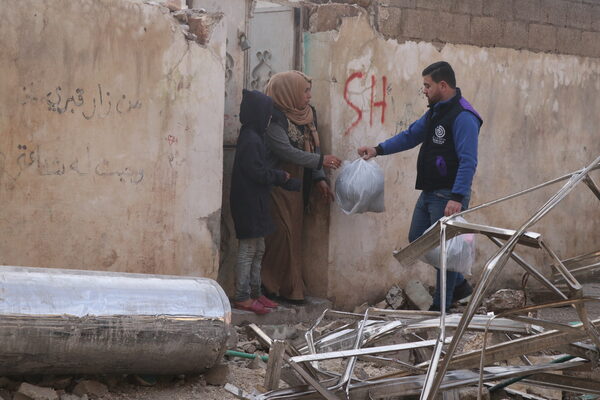 Ein Mann reicht einer Frau eine Tüte mit Lebensmitteln