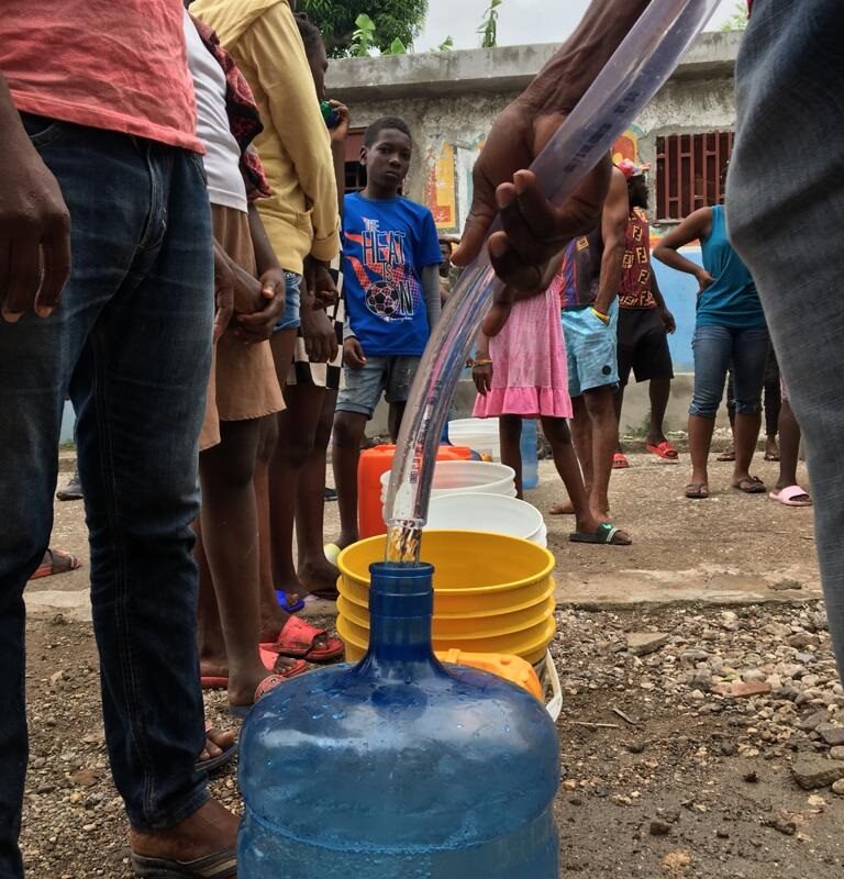 junge Haitianer lassen sich Trinkwasser abfüllen
