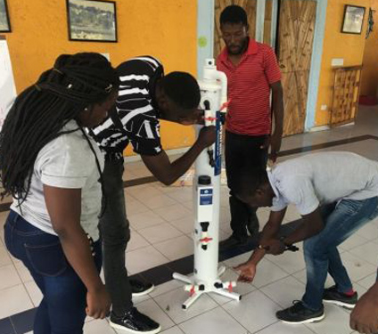 Haitianer probieren bei einer Schulung eine Trinwasseraufberetiutngsanlage aus 