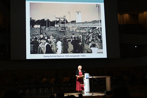Festvortrag von Prof. Simone Lässing, im Hintergrund Bild des Georg-Arnhold-Bads im Jahr 1930.