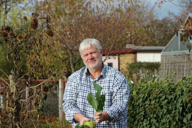 Frank Hoffmann im Garten mit einer Kohlrabipflanze in der Hand
