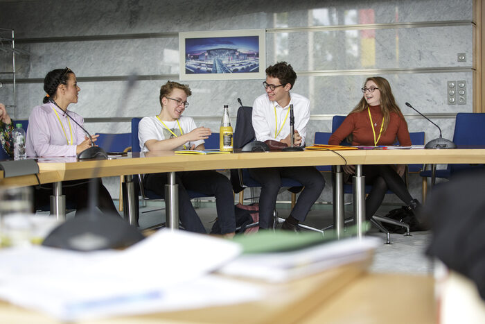 Four students sit around a table and debate how to make laws to protect the environment