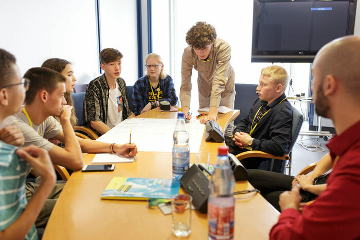Students sit around a table and discuss what it needs to be a European Youth Capital