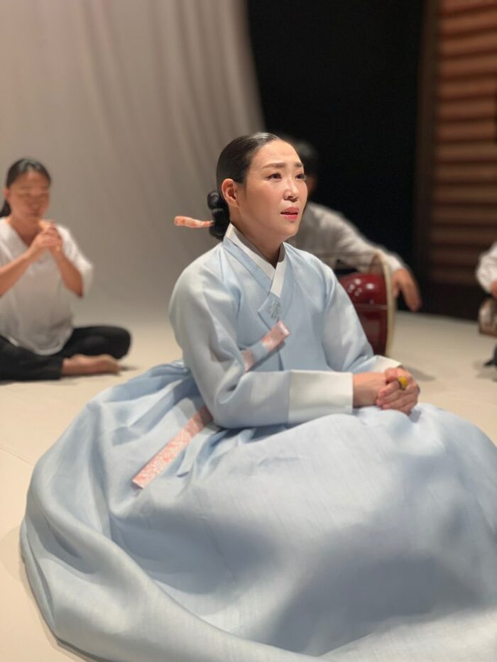 Sitzende Koreanerin in hellblauem traditionellen Kostüm