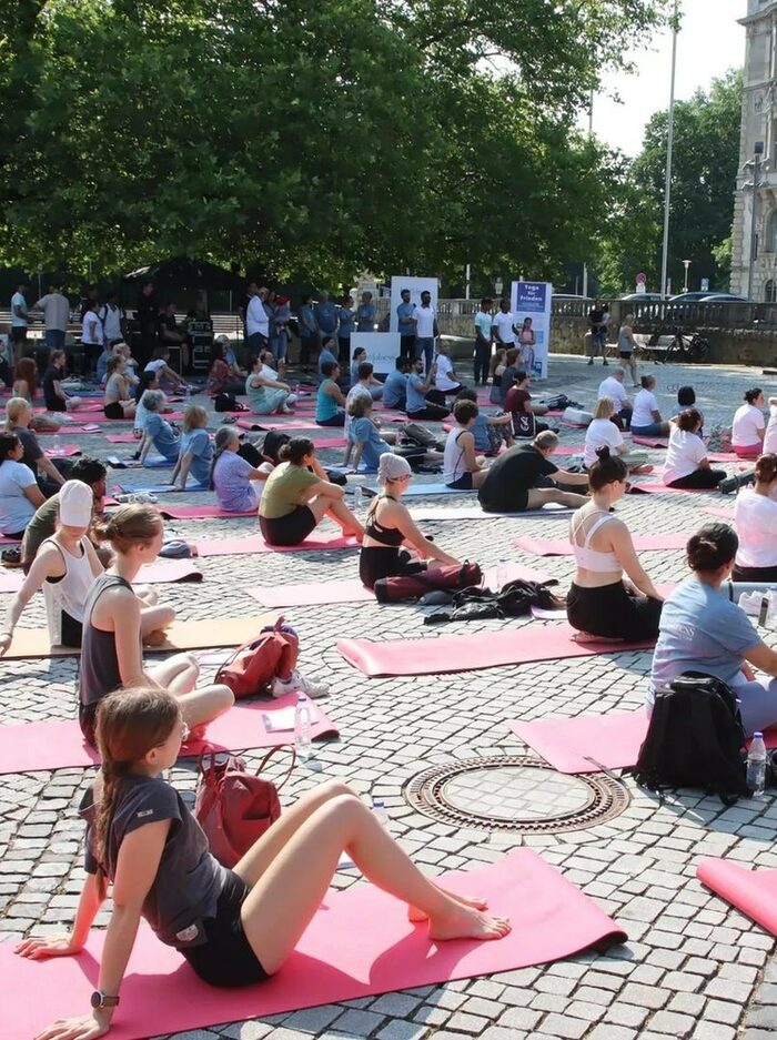 Menschen sitzen auf Yogamatten und schauen auf eine Leinwand