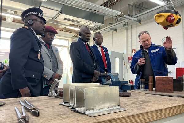 Ein Mann erklärt vier Männern mit Kopfhörern einen Herstellungsprozess