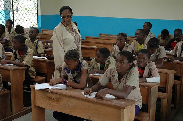 Klassenzimmer mit Schülern in alten Sitzbänken und ihren Lehrer beim Unterricht in der Schule Nganga Lincolo