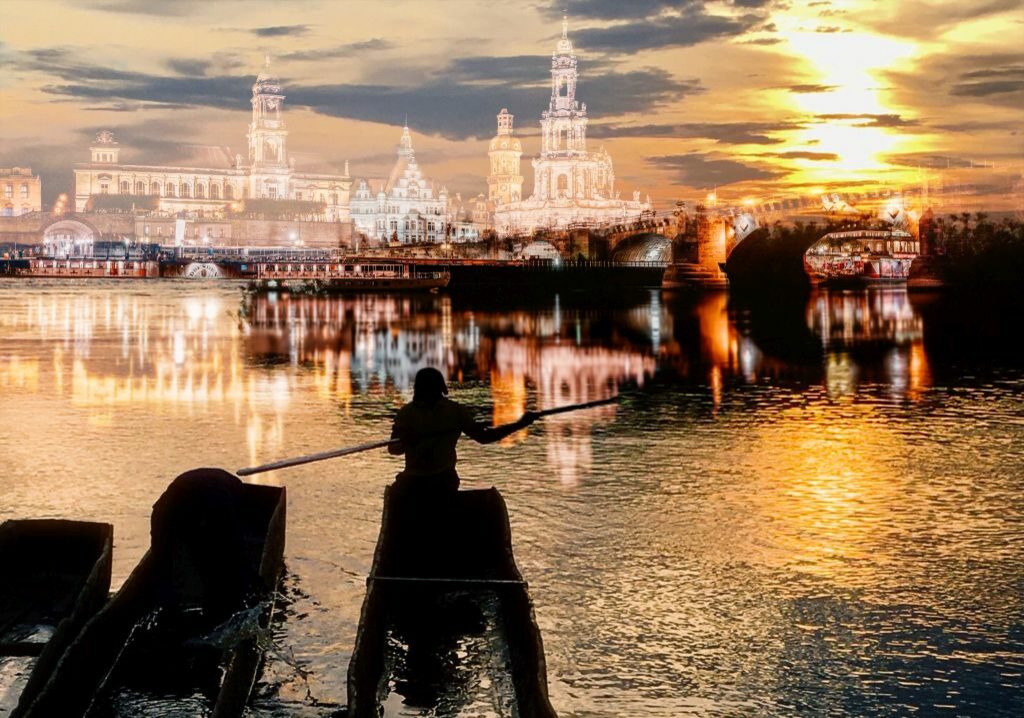 Zu sehen ist ein Fluss - die Elbe, der Kongo mit afrikanischen Booten und einen Menschen im Boot vor der Stadtsilhouette von Dresden im Sonnenunteregang