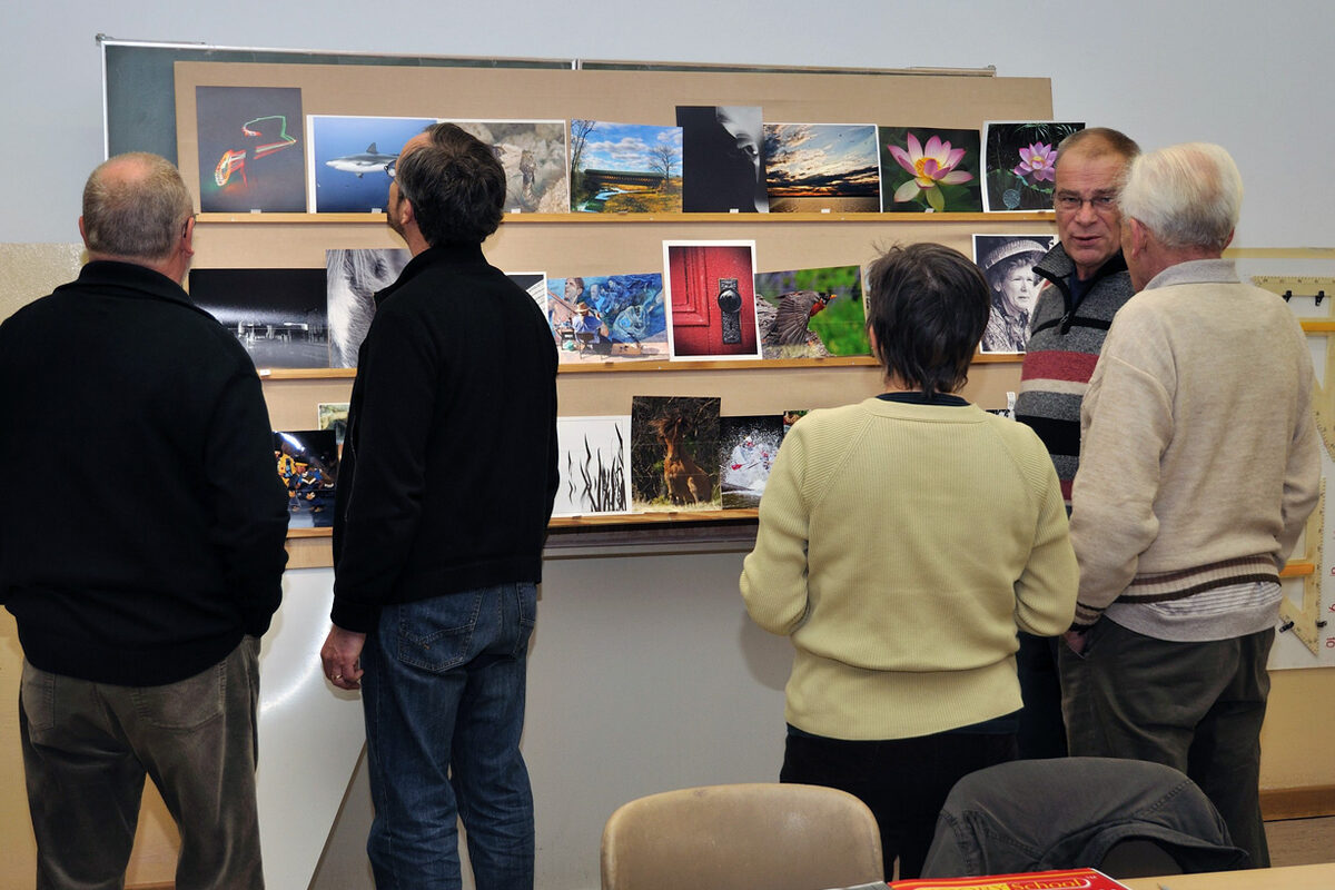 Menschen betrachten eine Fotowand.