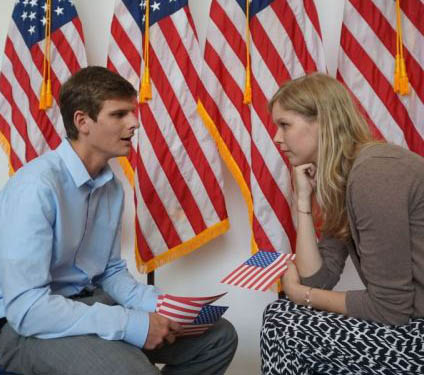 Studierende sitzen vor der US-Flagge und unterhalten sich beim Speed Dating im US-Generalkonsulat Leipzig