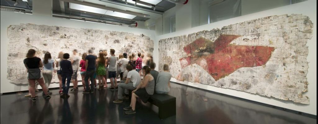 Besuchergruppe vor großforamtigen Collagen in der Ausstellung "Im Kreuzfeuer" 2014 im Stadtmuseum