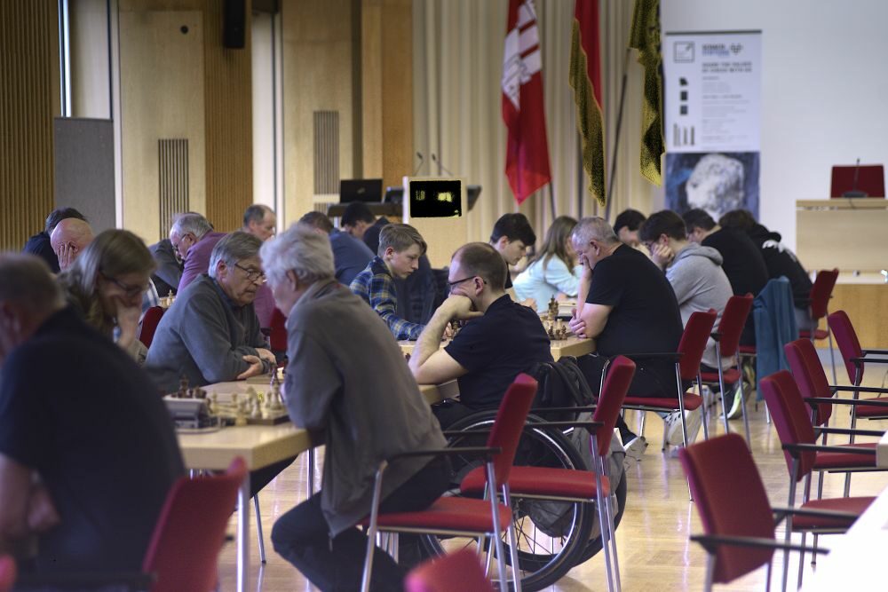 viele SpielerInnen an langen Tischreihen mit Schachbrettern