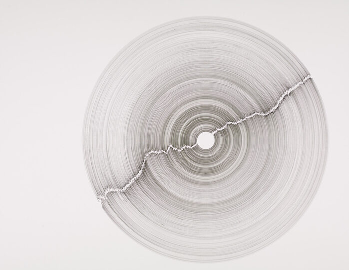 Kunst: Zeichnung "Ein Riss geht durch die Mitte" von Frieder Falk, zu sehen ist ein Kreis, der Baumringen ähnelt und durch die Mitte gespalten ist
