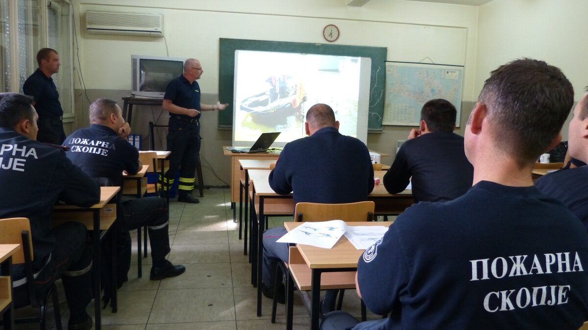 Feuerwehrmänner aus Skopje sitzen in einem Seminarraum und verfolgen die Vortrag eines Kollegen der Feuerwehr Dresden