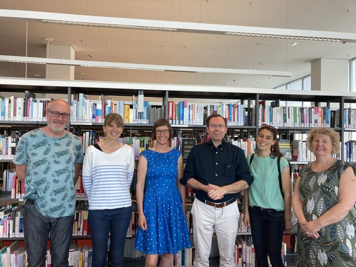 6 Menschen vor einem großen Bücherregal