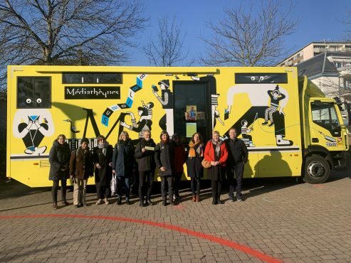 mobile Bibliothek in Straßburg, genannt Bibliobus, in einem gelben Bus, davor Gruppe von Menschen