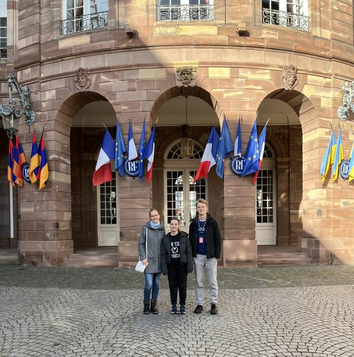 Dresdner SchülerInnen des Romain-Rolland-Gymnasiums vor einem Gebäude mit Fahnen in Straßburg