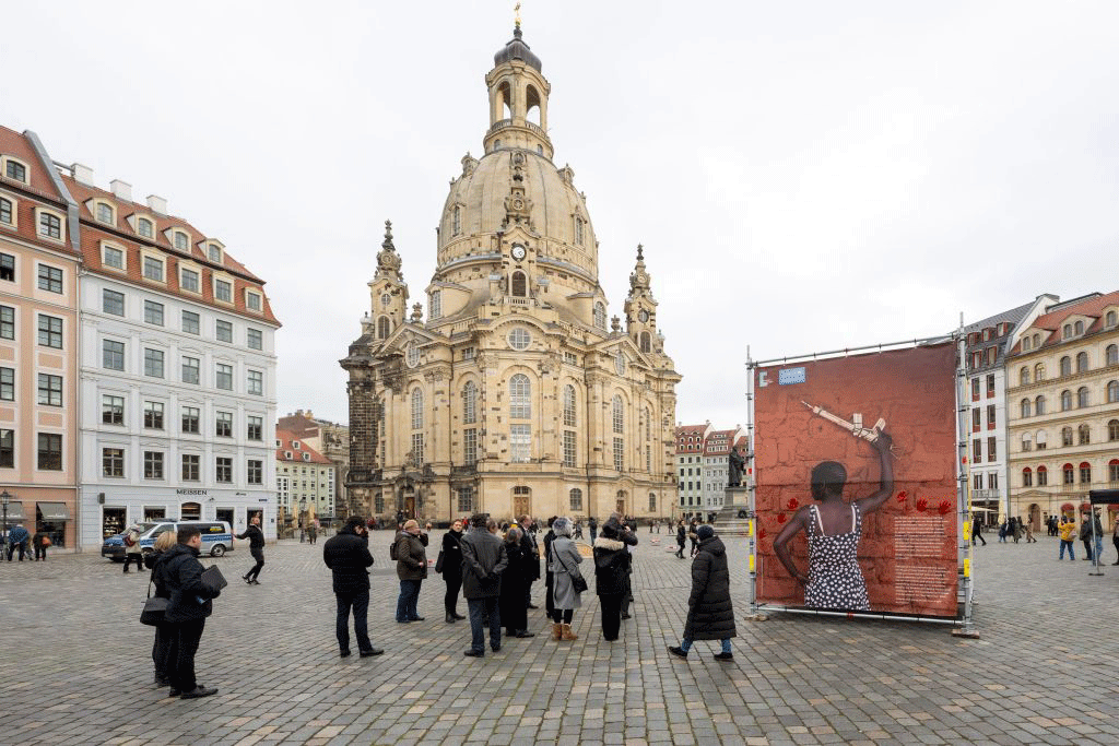 Menschen am Plakatkubus auf dem Neumarkt, im Hintergrund die Frauenkirche