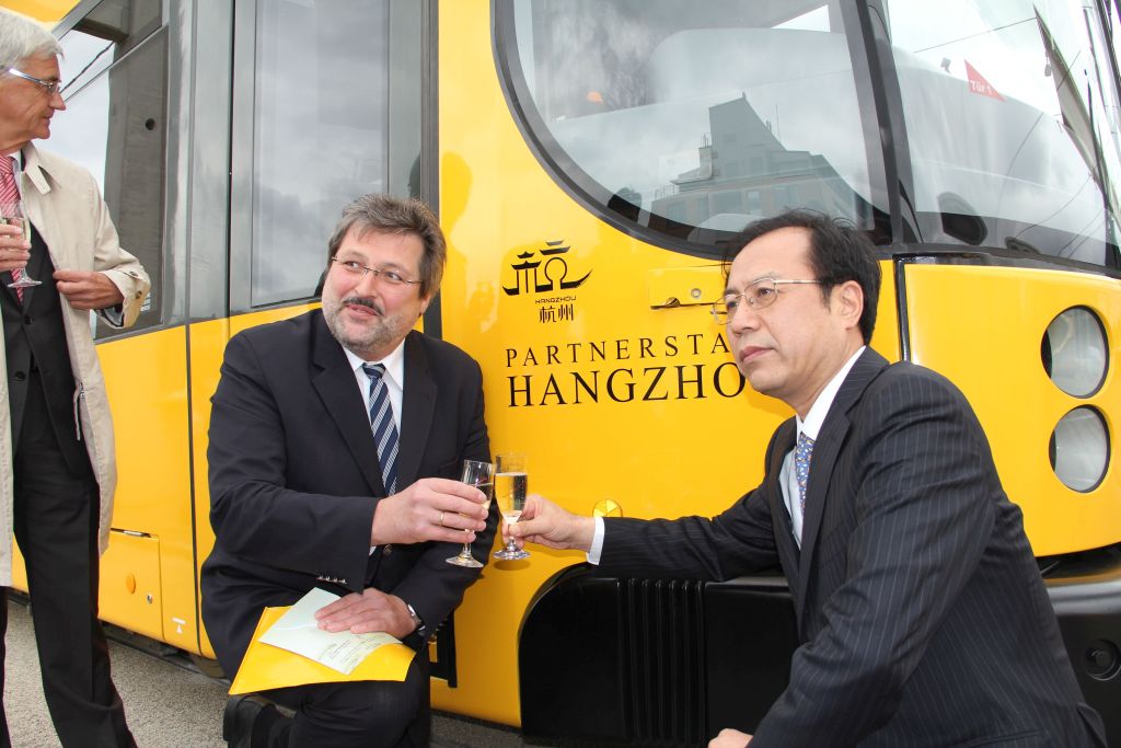 Vertreter aus Hangzhou mit dem Dresdner Stadtentwicklungsbürgermeister vor dem Schriftzug "Partnerstadt Hangzhou" der Hangzou-Bahn