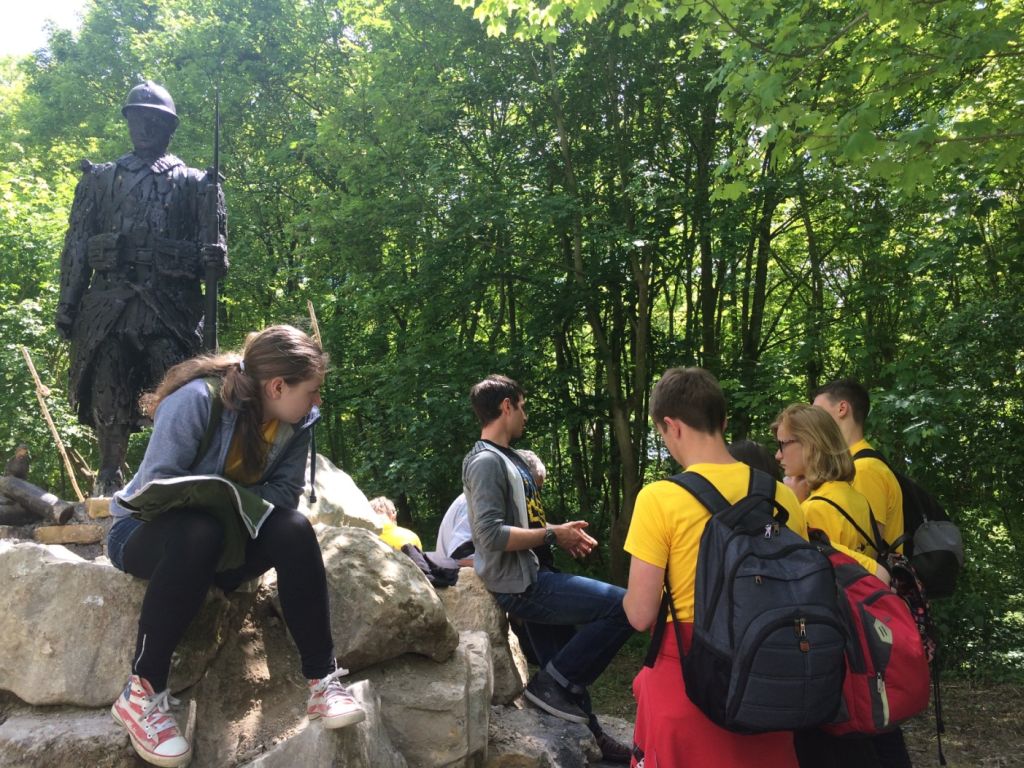 Schülerinnen und Schüler der Förderschule Makarenko sitzen an einem Denkmal zum 1. Weltkrieg in Frankreich