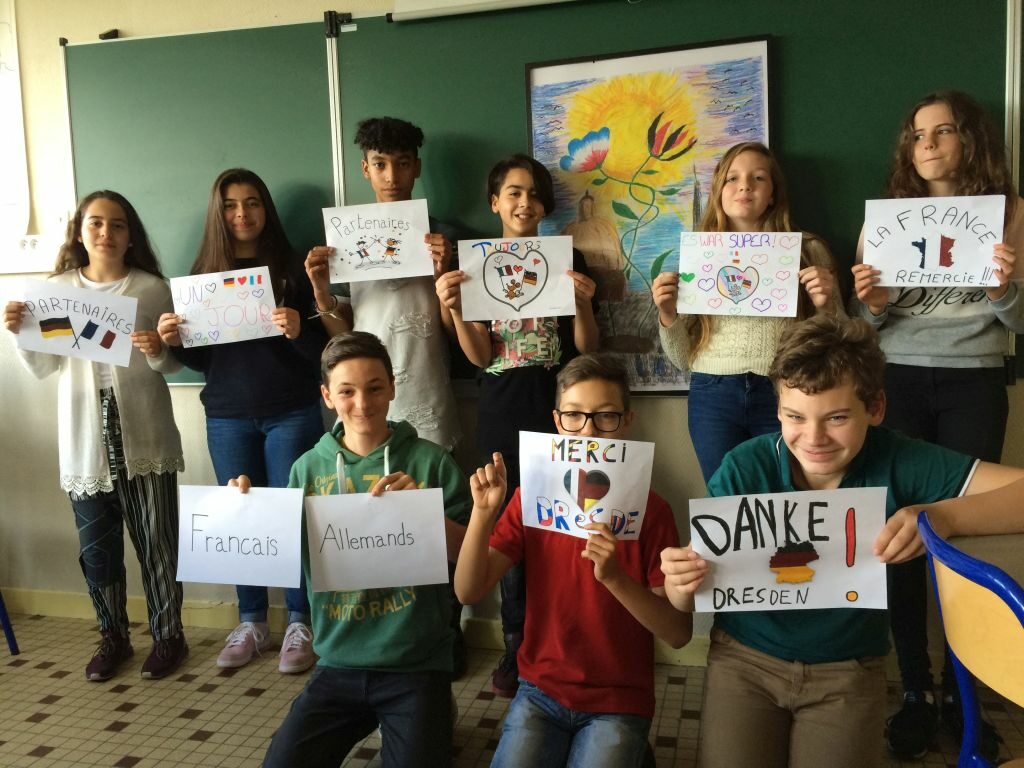 Ein Gruppenfoto: Schüler des Collége Le Ried aus Straßburg-Bischheim bedanken sich mit gestalteten Schildern mit dem Wort "Danke", die sich hochhalten, bei der OS Pieschen für die Gastfreundschaft
