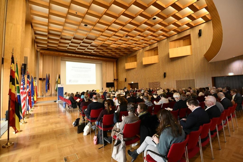 KongressteilnehmerInnen schauen einen Film im vollbesetzten den Plenarsaal des Neuen Rathauses Dresden