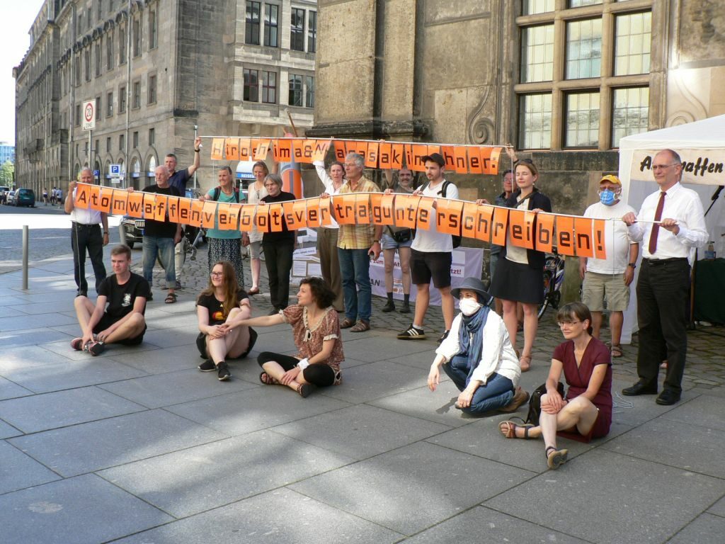 BesucherInnen der Mahnwache mit Banner: Hiroshima & Nagasaki mahnen: Atomwaffensperrvertrag unterschreiben!