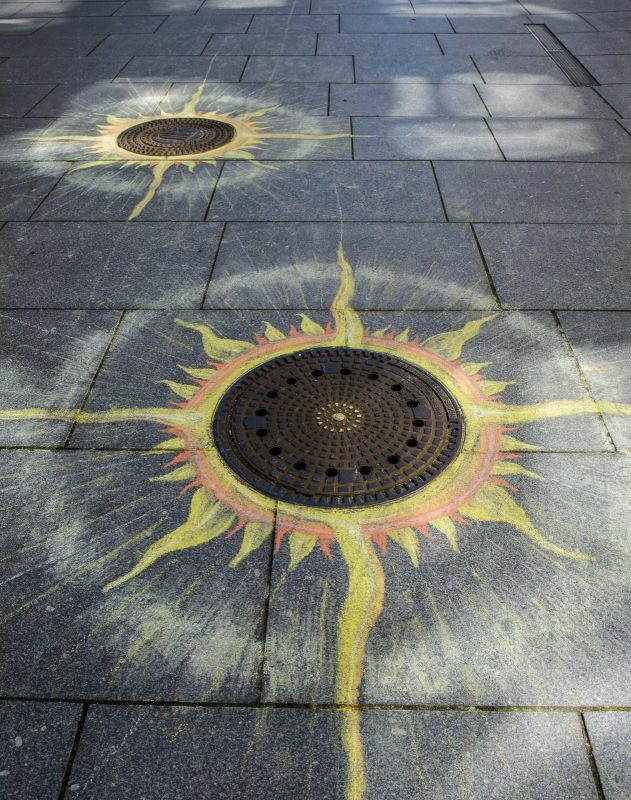 mit Farbkreide bemalte Gullidecke auf der Kreuzstraße, Motiv Sonne
