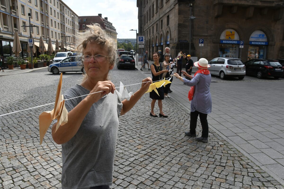 Menschenkette mit Origami-Kranichen beim Spannen der Kette über die Kreuzstraße