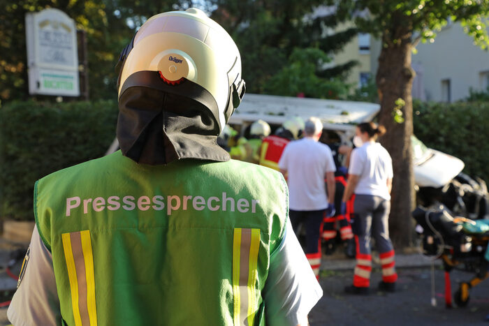 Der Pressesprecher ist mit einer grünen Funktionsweste gekennzeichnet.