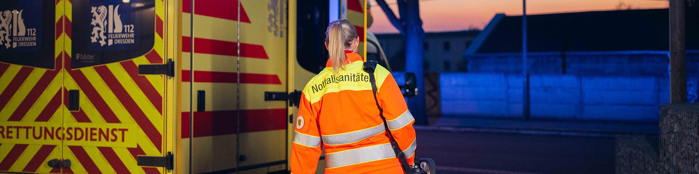 Notfallsanitäterin neben einem Rettungsdienstfahrzeug