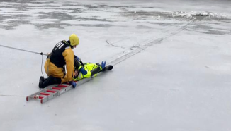 Ein Feuerwehrmann bei der Rettung einer Person, die ins Eis eingebrochen ist.