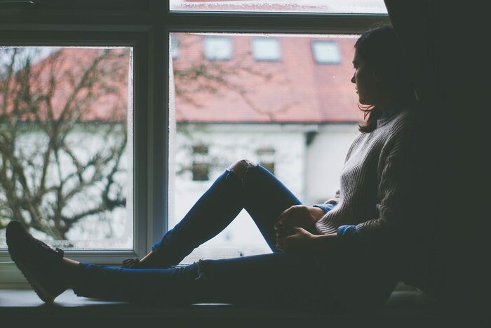 eine Frau sitzt einsam an einem Fenster und blickt nach draußen