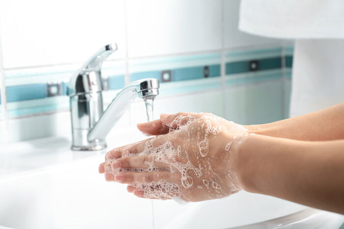 eine Frau wäscht ihre Hände im Waschbecken mit Wasser und Seife