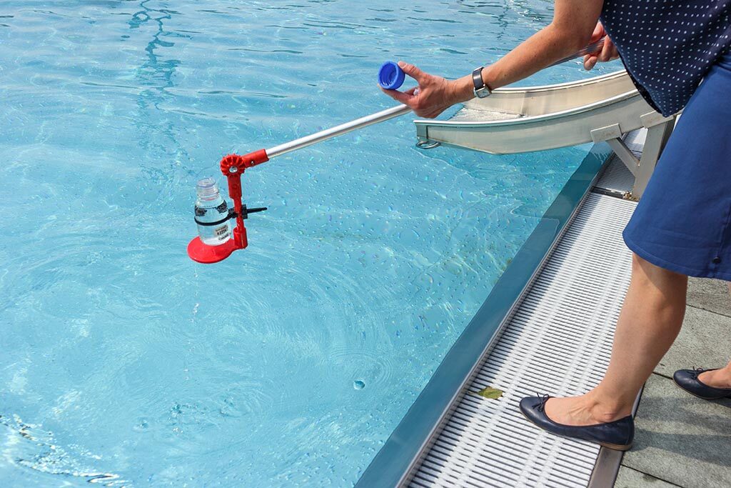 Probenentnahme aus einem Schwimmbecken zur Prüfung der Wasserqualität