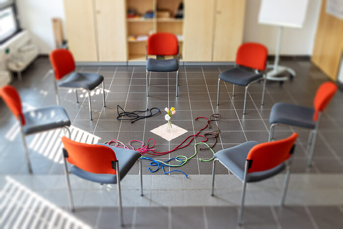 Kreis aus sieben Stühlen mit Material zur Gruppenarbeit