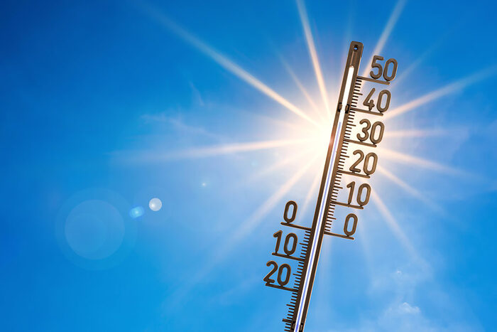 Ein Thermometer zeigt 35 Grad Celsius an. Dahinter strahlt die Sonne.