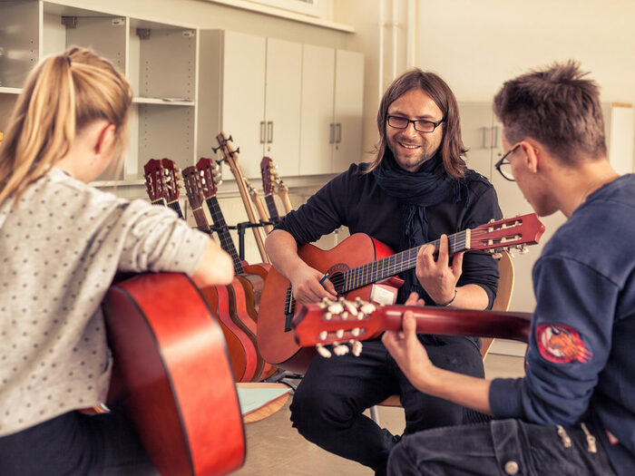 3 junge Menschen spielen Gitarre