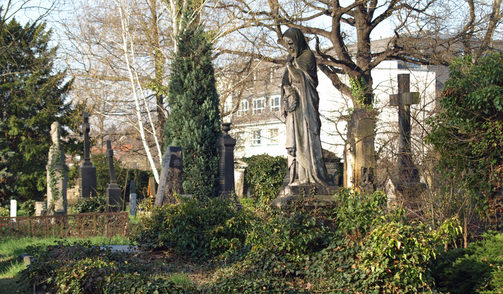 Friedhof mit alten Skulpturen und Steinkreuz