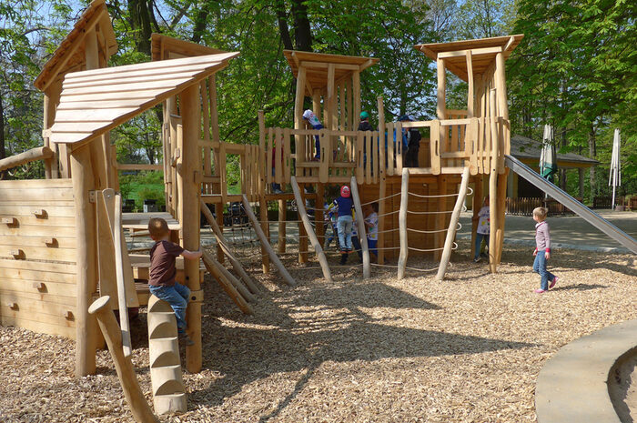 Kinder auf Spielplatz mit Holzklettergeräten