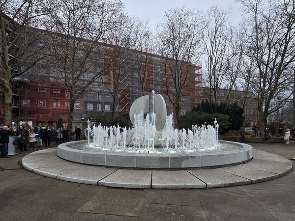 Krachtbrunnen Ost zur Wiederinbetriebnahme Dezember 2025: kreisrunde Brunnenschale, mittig die Brunnenfigur mit Metallkugel; das Wasser kommt aus den kreisförmig angeordneten Düsen