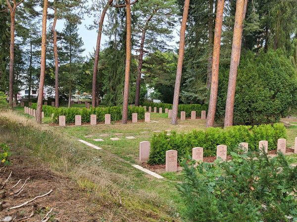 sowjetischer Garnisonsfriedhof mit den wieder aufgestellten Grabsteinen, Bepflanzung und Bäume im Hintergrund