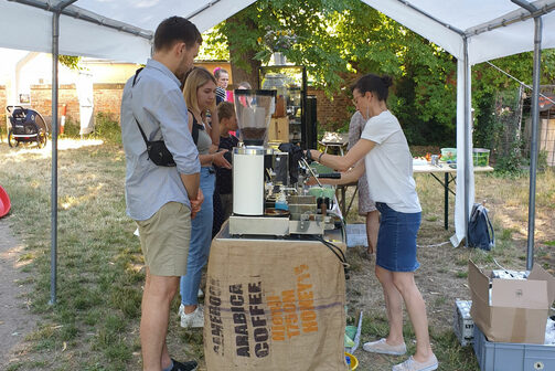 Menschen holen sich an einem kleinen Stand unter einem Pavillon Kaffee und Getränke.