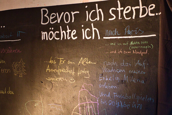 schwarze Tafel, darauf mit Kreide geschriebene Gedanken der Besucher zum Thema "Bevor ich strebe, möchte ich ..."