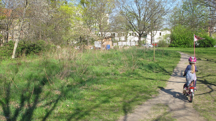 Blick auf den Park, rechts im Vordergrund ein Mädchen auf einem Fahrrad von hinten zu sehen