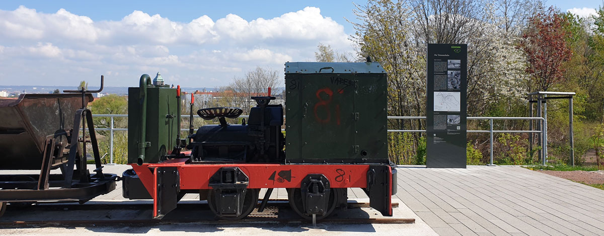 Lokomotive mit Lore und Informationsstele, im Hintergrund Blick auf Dresden