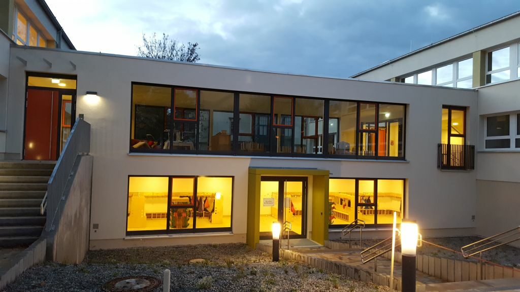 Blick bei Abend auf den beleuchteten Haupteingang