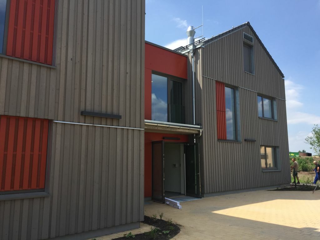 Blick auf den Eingangsbereich mit braun roter Fassade und Teile vom Hof